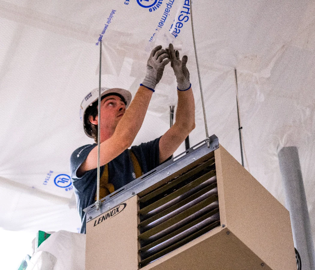 Worker installing TuffNet debris netting above operational facility